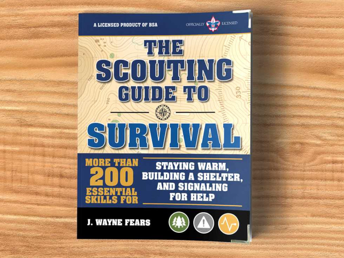 Book titled 'The Scouting Guide to Survival' on a wooden surface