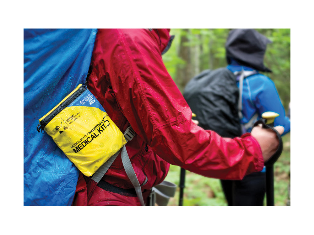 A hiker with the Adventure Medical Ultralight .5 Medical Kit attached to his backpack